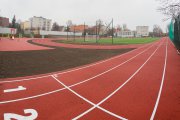 Kompleks sportowy. Widoczny fragment placu zabaw dla najmłodszych, bieżnia i boisko do piłki nożnej