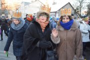 Orszak idzie ulicą Ściegiennego. Na pierwszym planie dwie kobiety w koronach. Jedna z nich pozdrawia fotografującego machając ręką