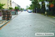Budowa ul. Morawskiej. Duży fragment ulicy i chodnika pokryty kostką. W oddali trwa budowa pozostałej części ulicy