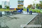 Pracownicy firmy budowlanej układają kostkę brukową parkingu przy ul. Szwanke. Z powodu padającego deszczu pracują w ubraniach przeciwdeszczowych