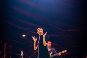Kasia Stankiewicz śpiewa do mikrofonu. Za nią widoczny gitarzysta.