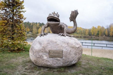 Legendarna Paskuda siedzi na wielkim kamieniu. Głowę ma podobną do głowy żaby, z tą rożnicą, że posiada dwa rzędy drobnych, ostrych zębow. Łapy i ogon przypominają części ciała starodawnego, baśniowego smoka.