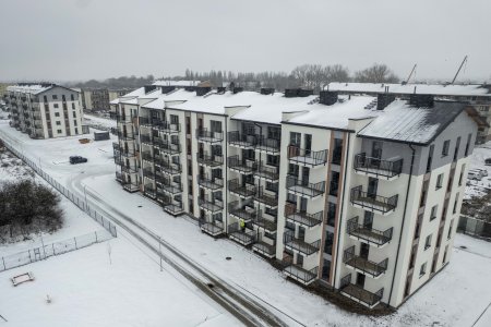 Zdjęcie dwoch budynkow wielorodzinnych w zimowej, śnieżnej aurze. Zdjęcie wykonano z wysokości, przy użyciu drona. Bloki mają po pięć kondygnacji. Na każdej znajduje się po 10 mieszkań. Mieszkania posiadają balkony.